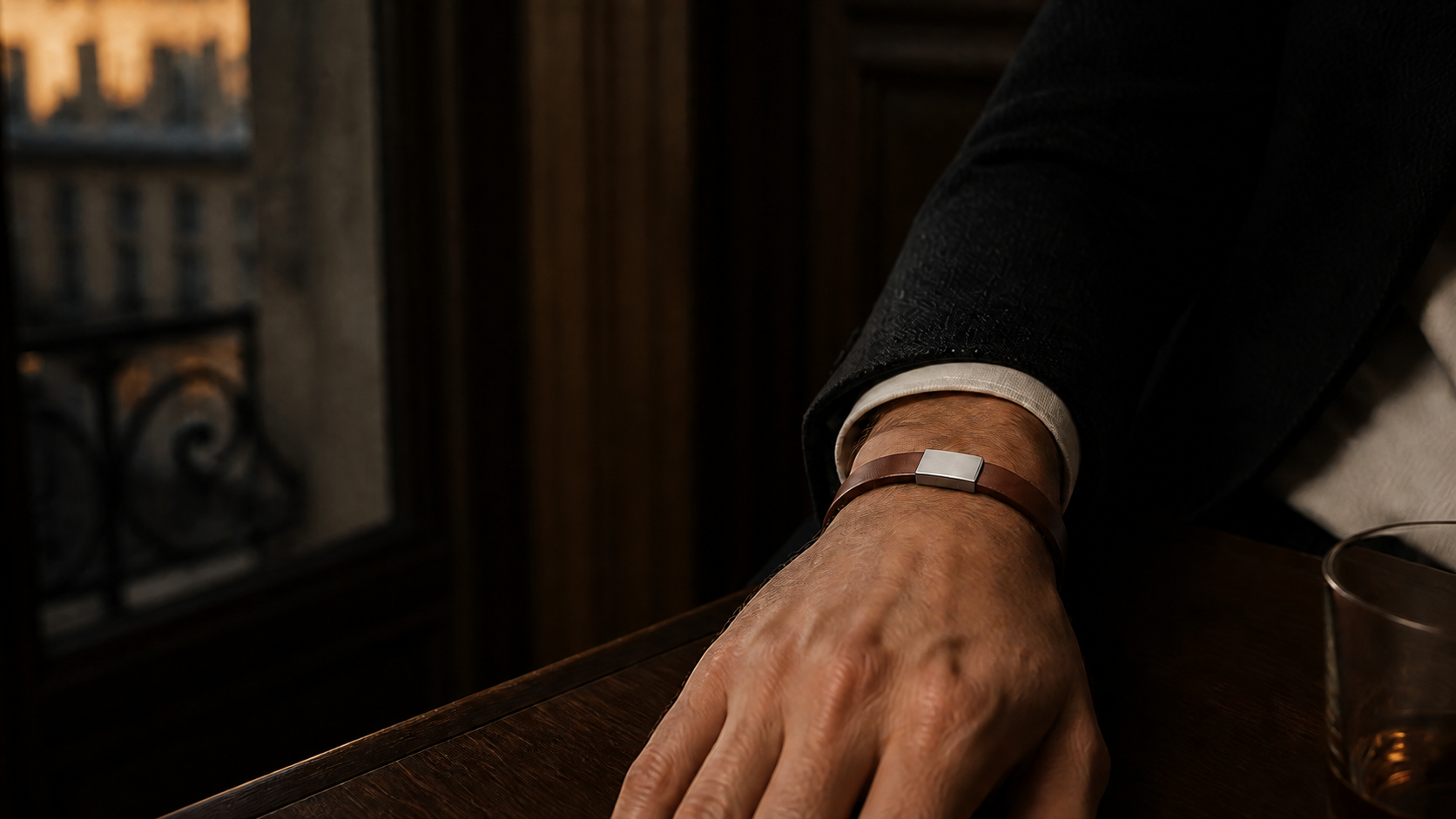Bracelet NORVAL en matière végane cognac, plaque finition argent, porté au poignet en fin de jour